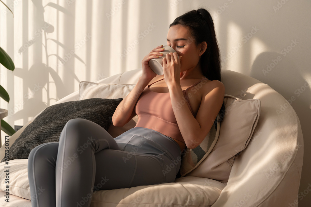 Young asian woman enjoying having coffee in living room at home Young asian woman enjoying having coffee in living room at home