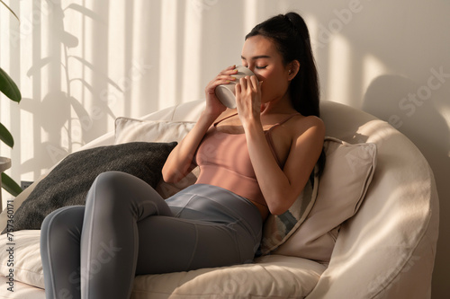 Young asian woman enjoying having coffee in living room at home