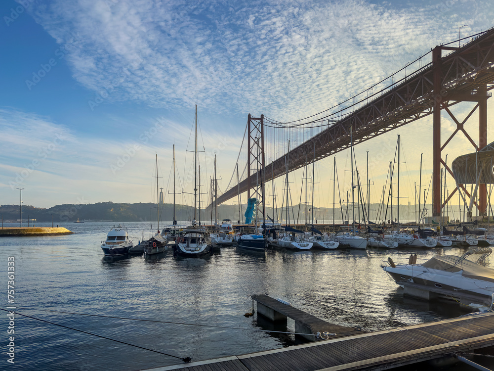 Lisbon docks with boats and views of the 25 de Abril bridge. With sunset.