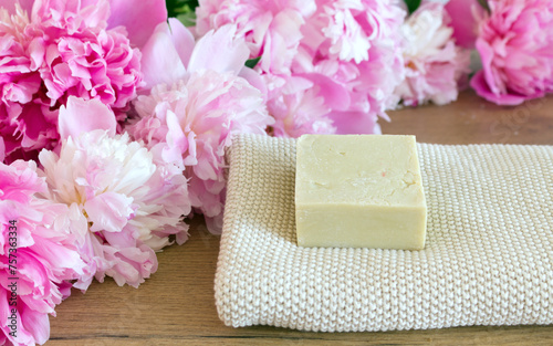 Closeup of hand-made herbal soap. Pink peonies. Spa concept. Skin product mockup scene. Cosmetic product.