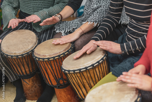 Women playing on the djembe drums during music therapy, drumming healing
