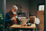 Portrait d'un homme photographe assis souriant quinquagénaire senior hipster élégant et stylé qui travaille sur un ordinateur dans un atelier créatif vintage