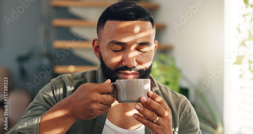 Smile, calm and man with coffee by window in apartment for relaxing weekend morning routine. Happy, peace and young male person drinking cappuccino, tea or latte in cup with aroma at modern home.