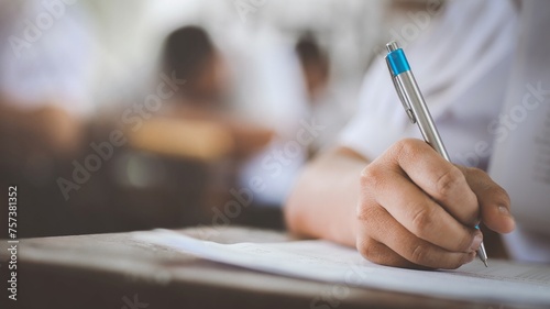 Close up hand of students reading and taking exam sheets exercises answer with stress in classroom