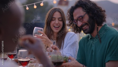 Smiling people having fun at reunion of friends BBQ food and beverage. Couple eating and drinking happiness on sunset at a terrace. Laughing group of multiracial friends celebrating a meal outdoor