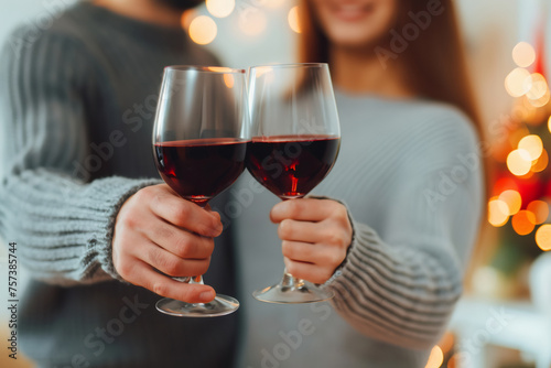 Happy wife and husband standing indoor clink glasses of red wine celebrate anniversary or house-warming close up focus on wineglasses. Life events, anniversary, St. Valentines Day celebration concept