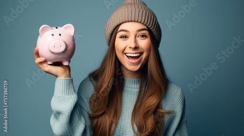 Smiling young girl holding a piggybank against blue background