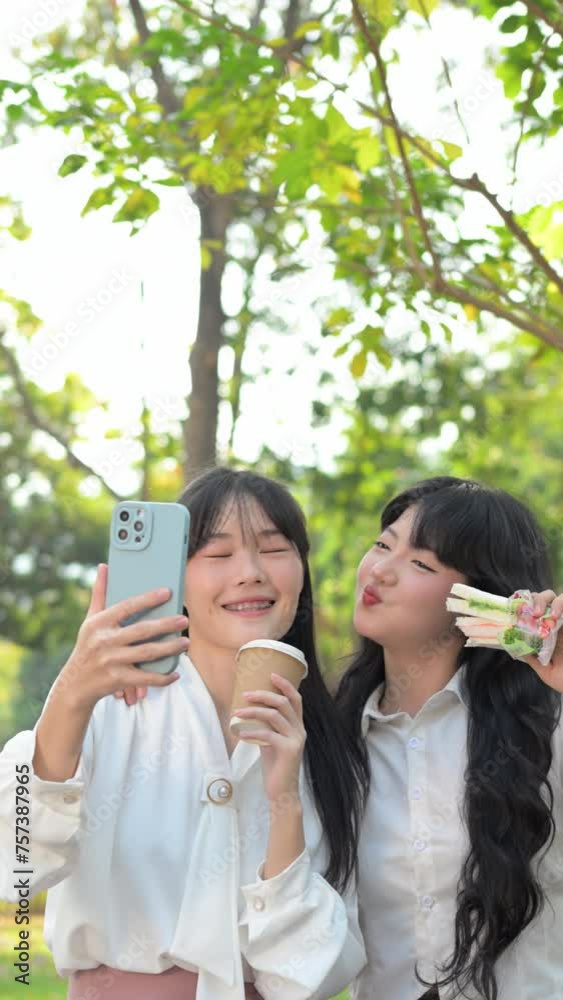 Two happy laughing colleagues taking a selfie in the park during break. Two happy laughing colleagues taking a selfie in the park during break.