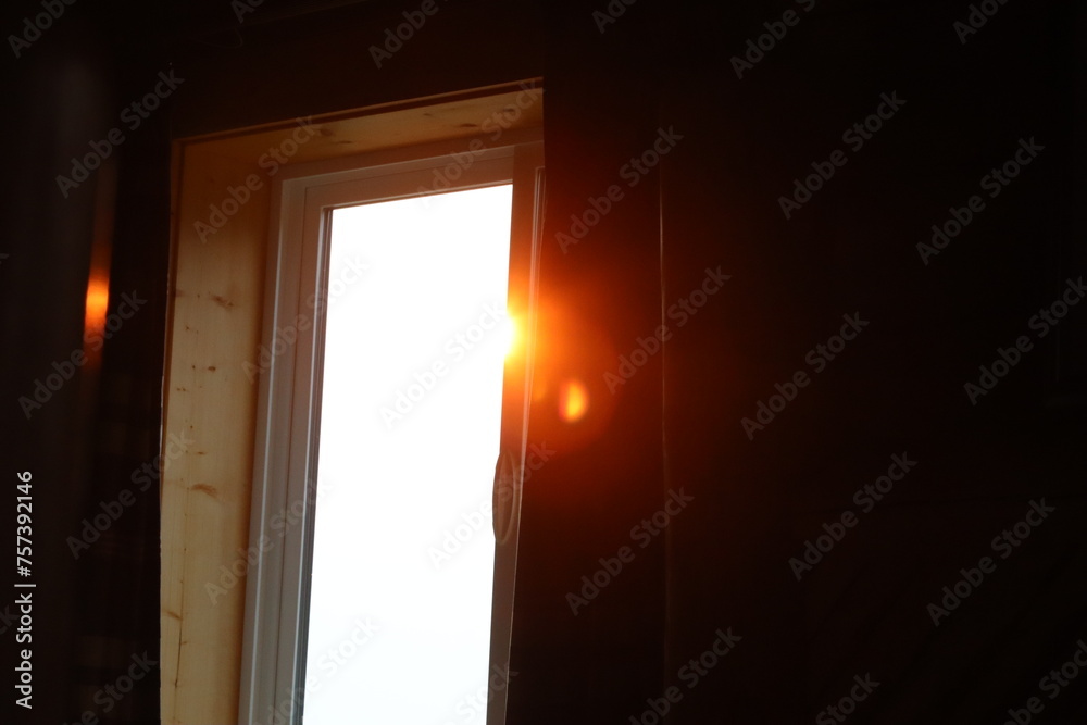 An orange beam of sunlight illuminates a cozy cabin home