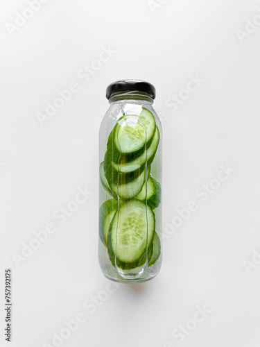Detox drink with sliced cucumber in inside glass bottle, isolated on white background. High angle view with copy space. Freshness and hydration concept for health and wellness design.