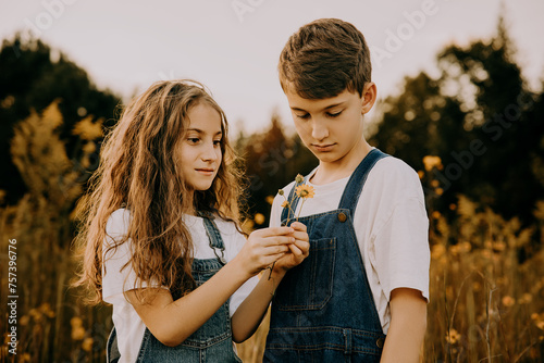 Two sibling kids out in the country picking flowers