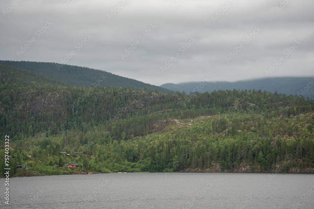 Landscape with a lake and green trees in the mountains and typical Norwegian wooden mountain houses.