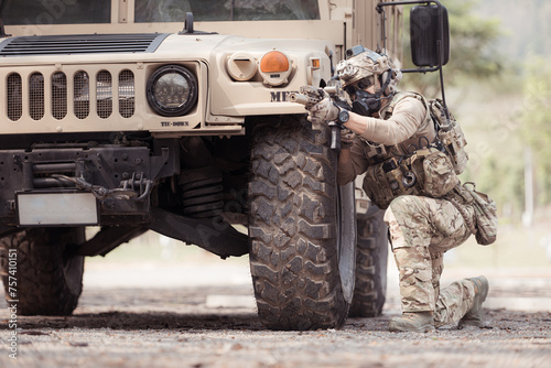 Soldiers in camouflage uniforms hold weapons ready to fire, By hiding on the side military communication vehicle