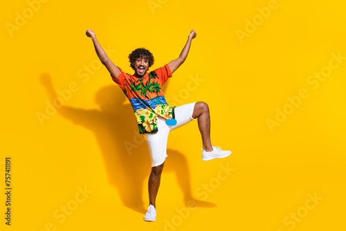 Full length photo of overjoyed guy wear hawaii print shirt raising fists up win betting scream yeah isolated on yellow color background