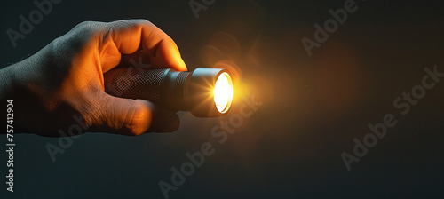 Hand holding a lit flashlight