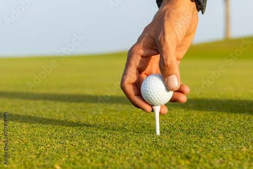 Anonymous golfer with dreadlocks placing ball on tee