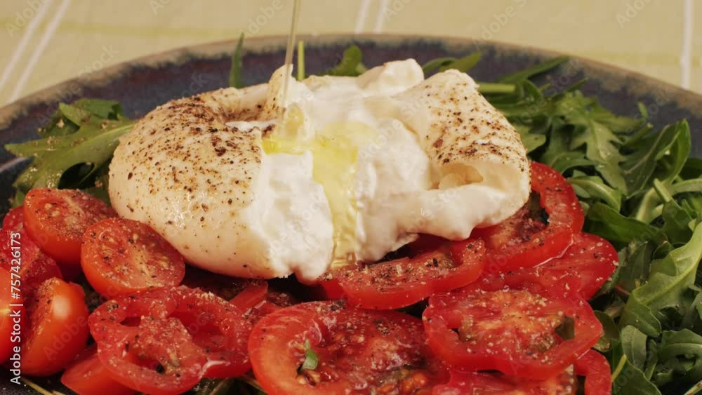 Burrata or Mozzarella cheese on fresh tomatoes and green arugula on plate close-up. From Italian cow's milk cheese made from mozzarella and cream.The outer casing is solid Burrata or Mozzarella cheese on fresh tomatoes and green arugula on plate close-up. From Italian cow's milk cheese made from mozzarella and cream.The outer casing is solid