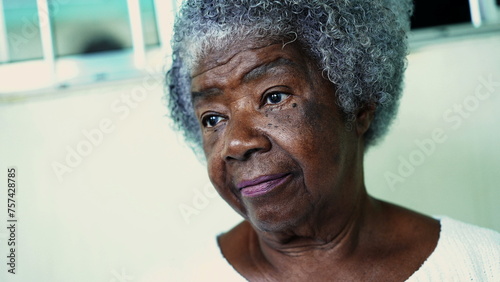 One pensive elderly black woman with gray hair and wrinkles. 80s African American portrait face close-up with thoughtful expression listening and interacting in conversation