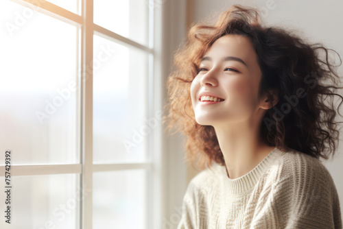 Cheerful young woman with curly hair laughing happily outdoors, against a modern city backdrop