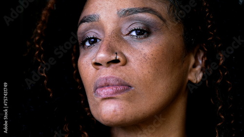 One serious black middle-aged woman close-up face looking at camera with intense gaze, upset judgemental expression of African American 50s lady