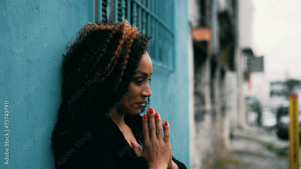 Preoccupied hispanic middle-aged latin woman of African descent in Prayer in urban environmen outside seeking hope and help during challenging times in deep mental contemplation