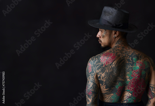 Back view of a man with black hat. Traditional yakuza member with his body entirely tattooed. With copy space for text. Gang member of the traditional Japanese mafia.