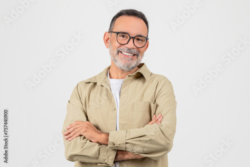 Cheerful senior man wearing stylish glasses standing with arms crossed