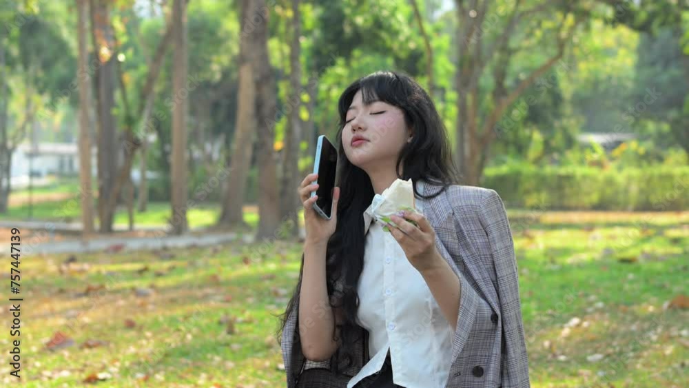 Beautiful young businesswoman answering phone call while eating sandwich at outdoor Beautiful young businesswoman answering phone call while eating sandwich at outdoor