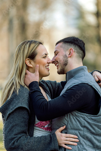 Happy couple in love. Stylish man with a beard and a beautiful girl on the autumn sunny day kissing. Portrait of a happy young couple enjoying a day in the park together .