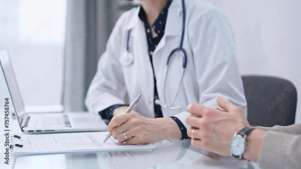 Doctor and patient. Female physician is sitting at the glass table, listening a senior man and writing medication history records. Medicine and pharmacy Doctor and patient. Female physician is sitting at the glass table, listening a senior man and writing medication history records. Medicine and pharmacy