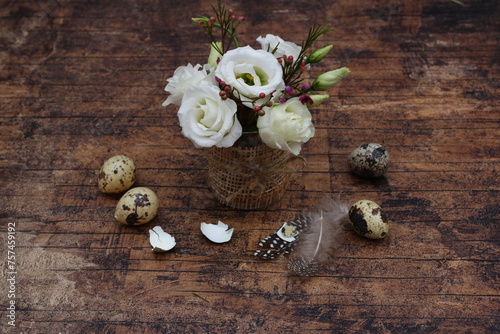 Blumenstrauß mit Wachteleiern auf rustikalem Holztisch.