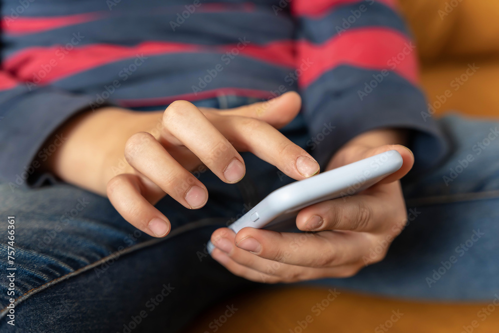  boy is sitting on the couch and using a smartphone