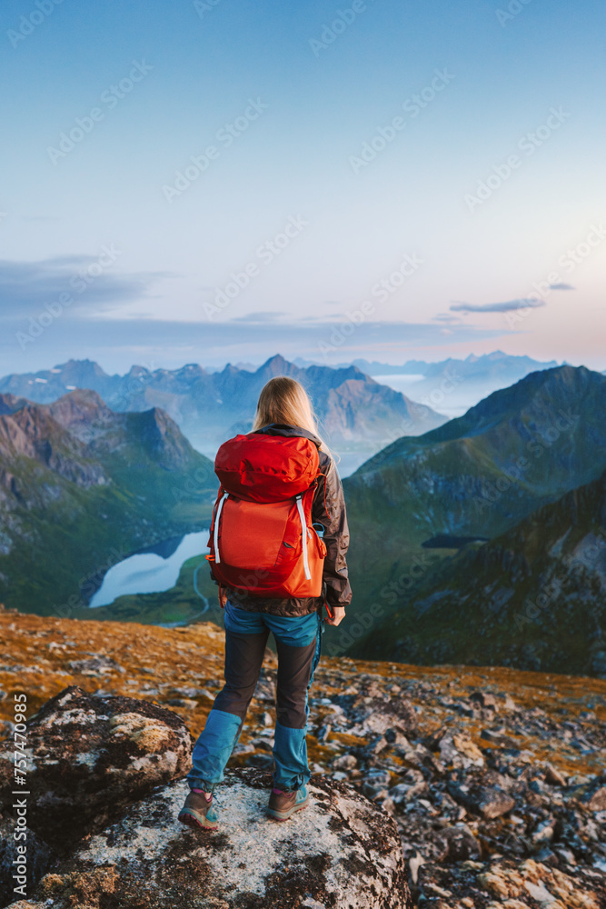 Traveler woman hiking in Norway solo in mountains of Lofoten islands girl tourist with red backpack traveling outdoor active healthy lifestyle summer vacations freedom adventure concept
