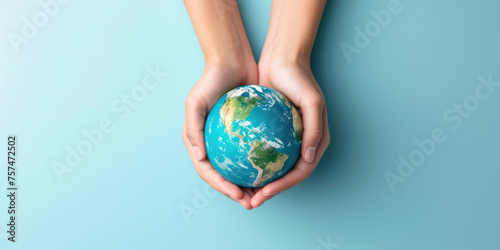 Two hands gently cradling a small globe against a serene blue background, symbolizing care and protection for the Earth.