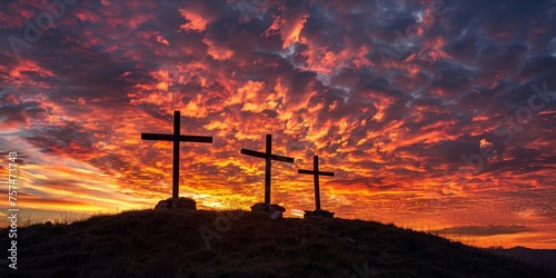 Three crosses on a hilltop at sunset with a dramatic sky.