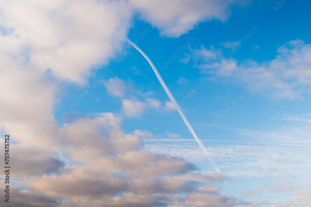 White clouds and condensation trail in the blue sky. Daylight, cloudy day. Nature, cloudscape, abstract, peaceful and freedom concept White clouds and condensation trail in the blue sky. Daylight, cloudy day. Nature, cloudscape, abstract, peaceful and freedom concept