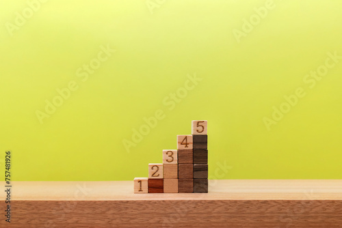 ブロックを積み上げた5段の階段が緑色の背景にあるステップアップの素材