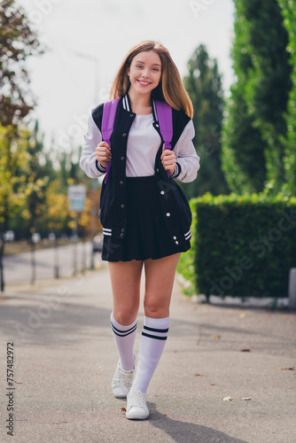 Full length vertical photo of lovely teenager lady walking schoolgirl wear trendy uniform garment autumn park sunny day background © deagreez
