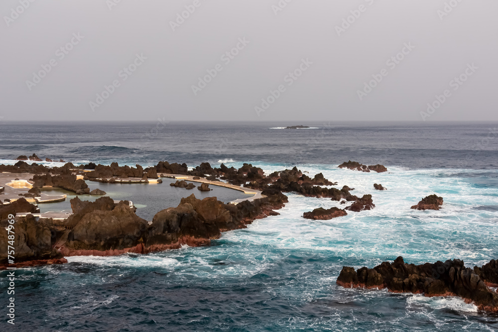 Natural lava pools with sunset view of volcanic rock formation Ilheu Mole in coastal town Porto Moniz, Madeira island, Portugal, Europe. Rugged coastline of Atlantic Ocean. Waves smashing shoreline Natural lava pools with sunset view of volcanic rock formation Ilheu Mole in coastal town Porto Moniz, Madeira island, Portugal, Europe. Rugged coastline of Atlantic Ocean. Waves smashing shoreline