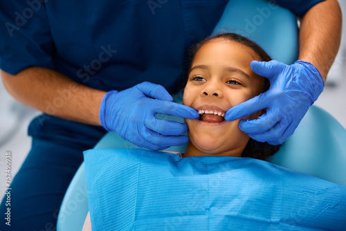 Canvastavla Small black girl getting her teeth checked by dentist at dental clinic