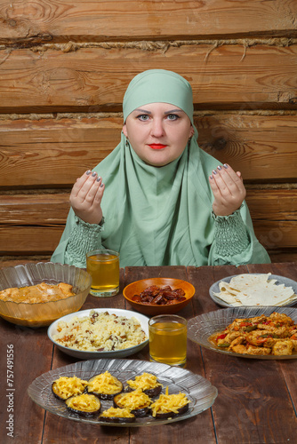 A young Muslim woman in a light khimar at the table says bismi llah during Ramadan iftar photo