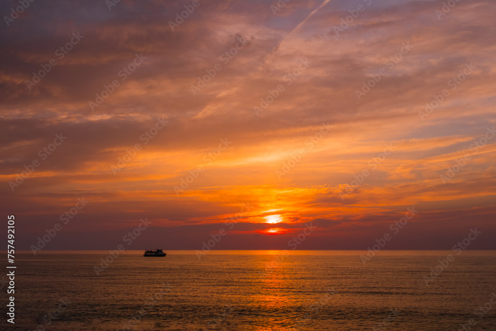 View of the amazing dramatic sunset sky with clouds and setting sun over the Black Sea surface in the evening. Pleasure boat is sailing. Summer, nature, tropical and cloudscape concept View of the amazing dramatic sunset sky with clouds and setting sun over the Black Sea surface in the evening. Pleasure boat is sailing. Summer, nature, tropical and cloudscape concept