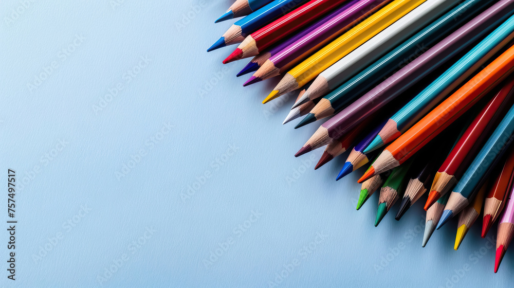 colored pencils arranged in one corner on a light blue background with copy space.