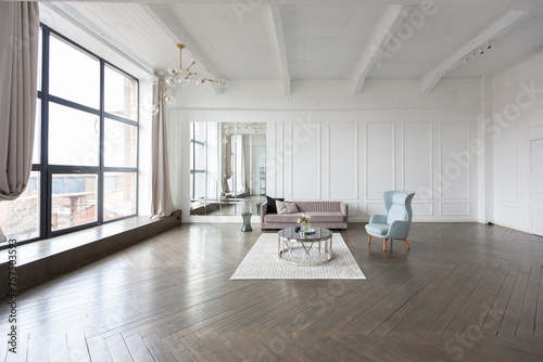 Modern luxury stylish apartment interior in pastel colors. a very bright room with huge windows filled with daylight. white walls, wooden parquet floors and a dark marble fireplace