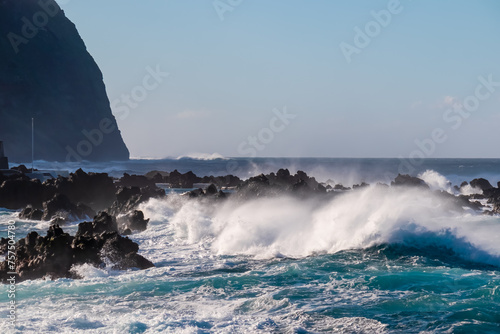 Strong waves smashing against jagged volcanic rocks on pristine coastline of coastal town Porto Moniz, Madeira island, Portugal, Europe. Powerful natural forces of majestic Atlantic Ocean. Seascape