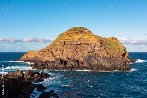 Panoramic view of volcanic rock formation Ilheu Mole in coastal town Porto Moniz, Madeira island, Portugal, Europe. Unique rugged coastline of majestic Atlantic Ocean. Waves smashing against shoreline photo