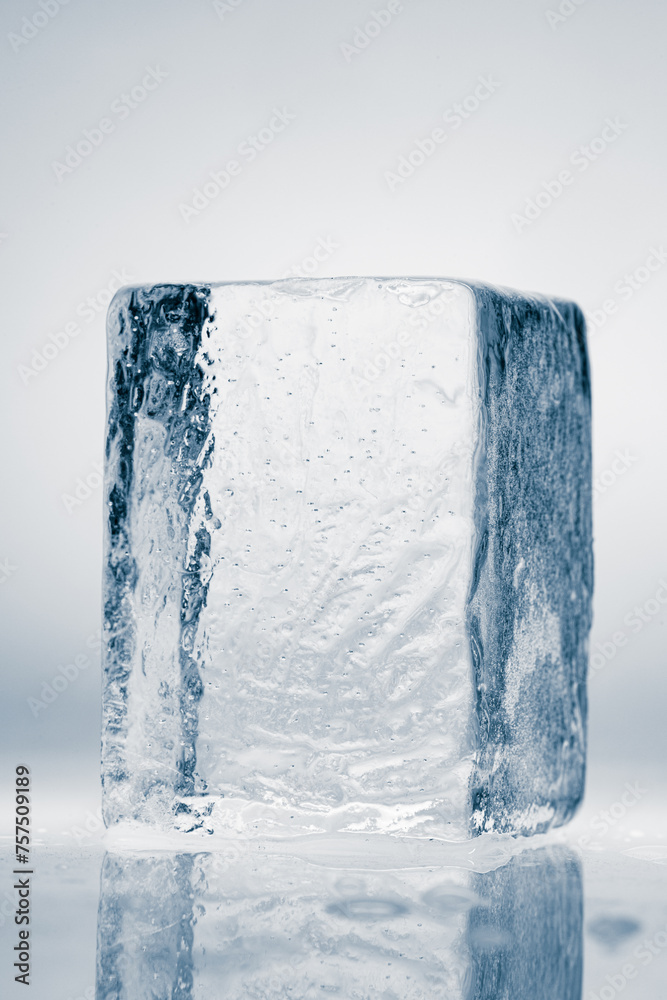 Natural crystal clear melting single ice cube on a white background with reflection. Natural crystal clear melting single ice cube on a white background with reflection.