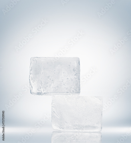 Crystal clear ice blocks in a rectangle form, stacked on a mirror surface on a white background.