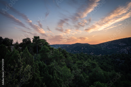 Sunset Among Trees in the Forest in the Mountains. Serene beauty of a forest in the mountain at sunset with clouds on a colorful sky over green trees, Alto Tajo Natural Park, Guadalajara, Spain.