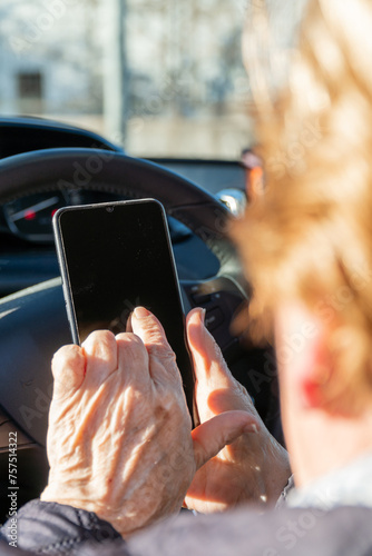 Elderly woman inside a car, touching the smartphone screen